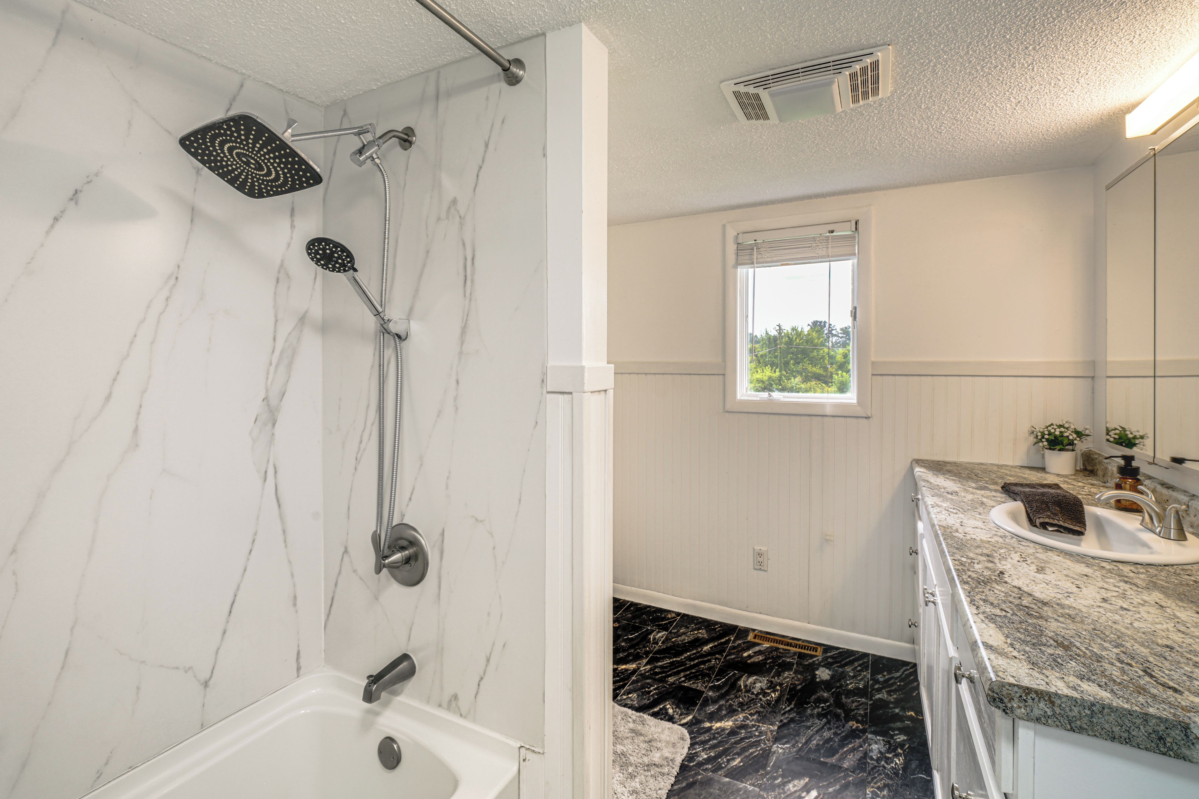 Ein Badezimmer mit Dusche, Waschbecken und Fenster.
