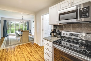 A modern kitchen with stainless steel appliances, a dining area with a view, and a wooden floor. - Featured on TV! Epic Indoor Pool • Sleeps 24 (Bridgman)
