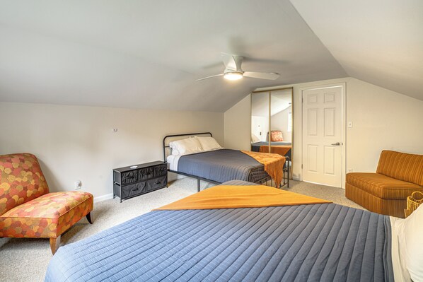 Quarto com cama, duas cadeiras, cômoda, espelho e porta.