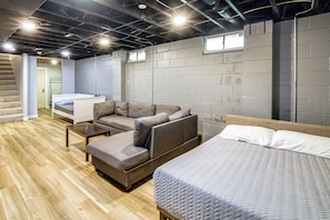 A modern, compact room with a sofa, a bed, and a small table. - Featured on TV! Epic Indoor Pool • Sleeps 24 (Bridgman)