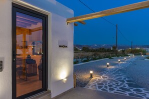 Una zona de recepción con puerta de vidrio, un cartel que dice "RECEPTION" y un sendero iluminado que lleva a una sala de estar.