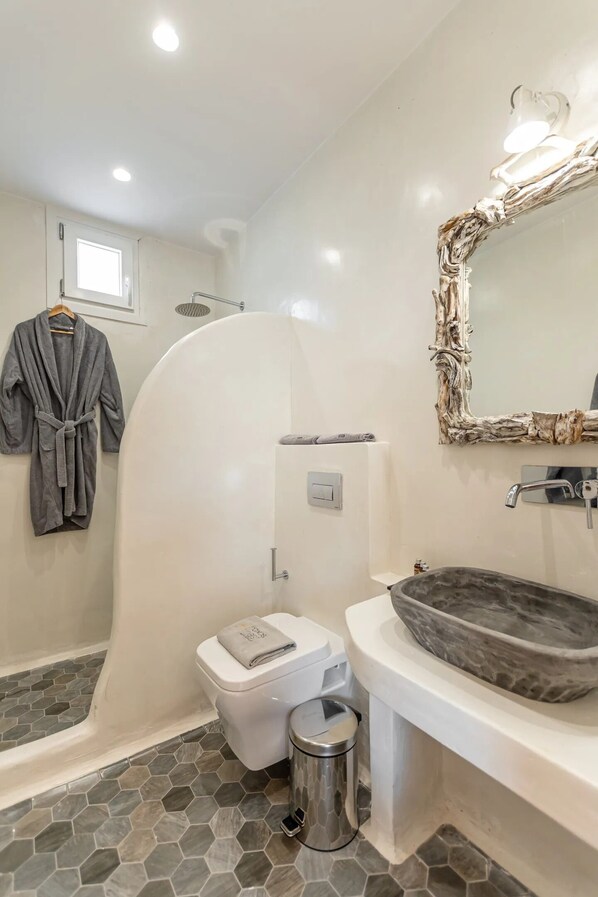 Une salle de bain avec une baignoire blanche, un grand miroir avec un cadre en bois naturel, des toilettes blanches et un lavabo en pierre.