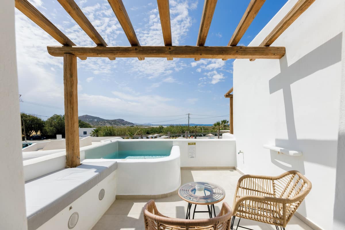 Una terraza en la azotea con hidromasaje, sillas de mimbre y una vista despejada del paisaje.