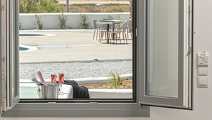 A room with a view of a beach, a dining area with outdoor furniture, and a small table with drinks and snacks.