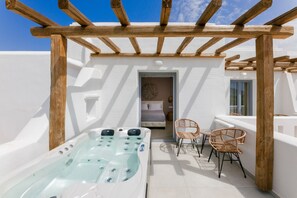 A rooftop terrace with a hot tub, wicker chairs, and a bedroom visible through an open door. - Naxos Finest Hotel & Villas (Naxos)