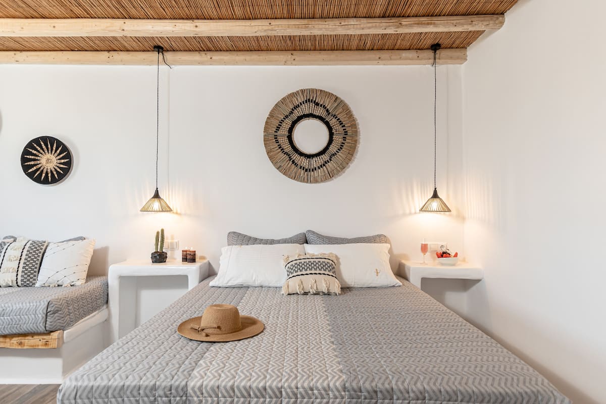 Un dormitorio con cama, mesitas de noche, decoración en la pared y un sombrero sobre la cama.