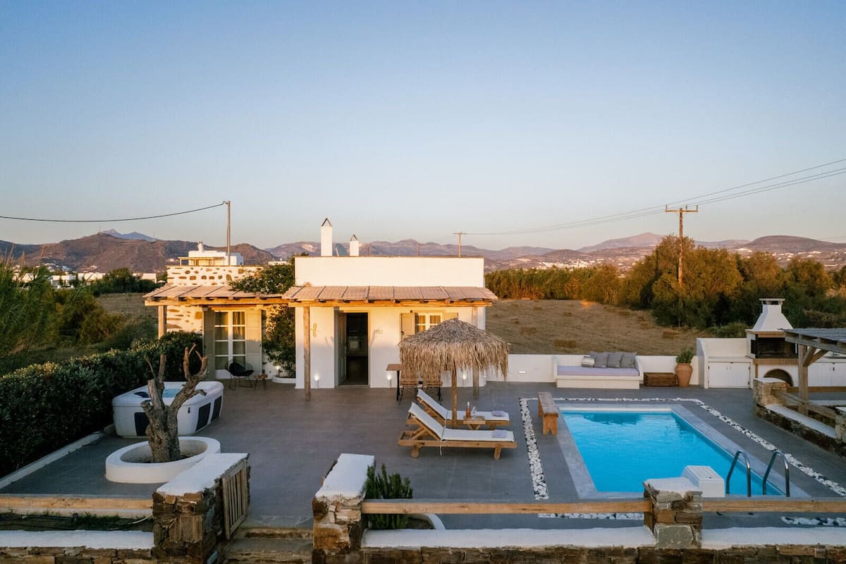 Una villa moderna con piscina, mobiliario exterior y vistas del paisaje circundante.
