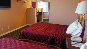 A hotel room with two beds, a desk with a telephone, a lamp, and a bathroom visible through an open door. - Americas Best Value Inn Seaside North (Seaside)