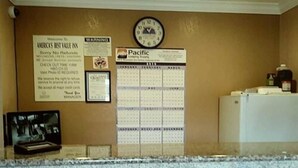 A reception area with a bulletin board displaying a welcome sign, a warning sign, a framed certificate, and a Pacific Airlines flyer. - Americas Best Value Inn Seaside North (Seaside)