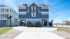 Une maison à deux étages avec un garage, une véranda et un petit jardin.