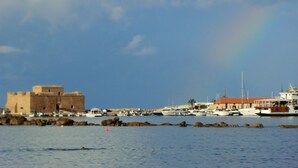 Kustlandschap met een historisch fort, boten en een regenboog.