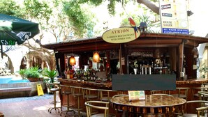 Een buitengebied met een bar en een bord waarop staat: Atrion Garden Restaurant heet u welkom.