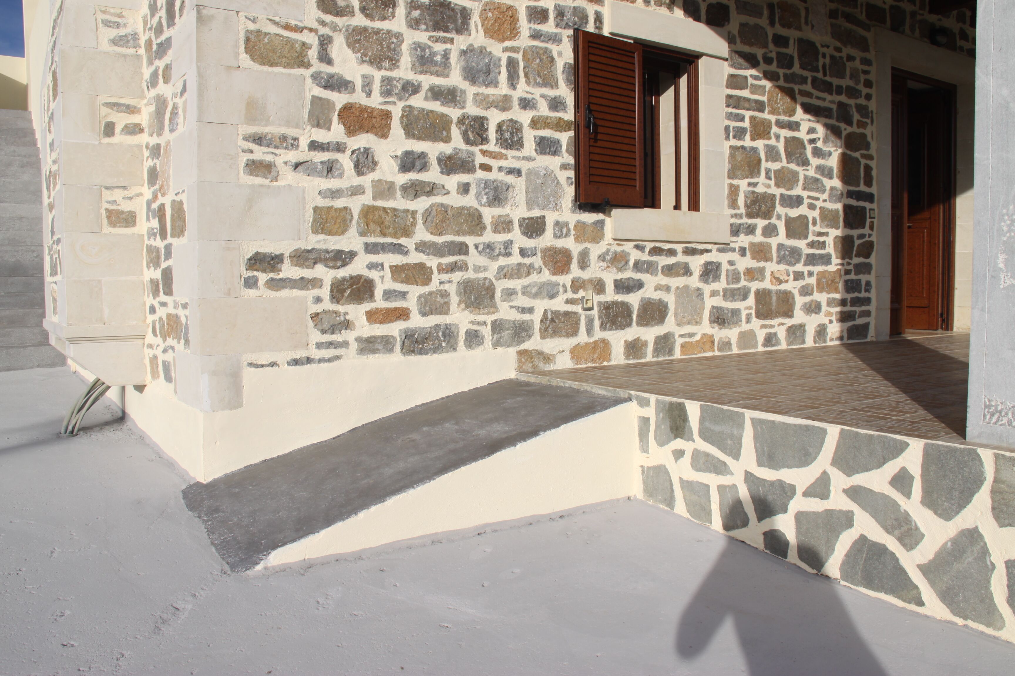 A stone building with a wooden door and a window with shutters.