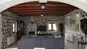 Ein Wohnzimmer mit Steinsäulen, einem grauen Sofa, einem Kamin und einem an der Wand befestigten Fernseher.