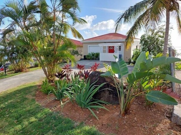 Un edificio con techo rojo, rodeado de plantas tropicales y palmeras.