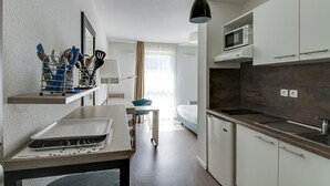 A modern kitchen with a microwave, sink, and a hanging light fixture. - Les Glenans Toulouse (Toulouse)