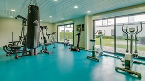 A gym with various exercise equipment, large windows, and a teal floor. - Les Glenans Toulouse (Toulouse)