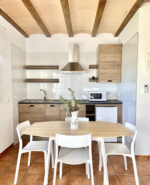 A modern kitchen with white cabinets, wooden countertops, a central island with chairs, and a decorative plant.