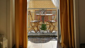 Un balcon avec une table et des chaises, des rideaux et une vue sur un immeuble.