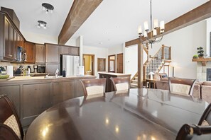 A spacious kitchen with wooden cabinets, a stainless steel refrigerator, and a dining area with a round table and chairs.