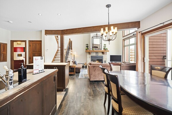 A spacious kitchen with a central island, a dining area with a large table, and a cozy living room with a fireplace.