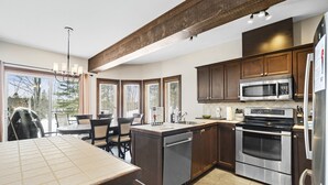 A modern kitchen with dark wooden cabinets, stainless steel appliances, and a large island with seating.
