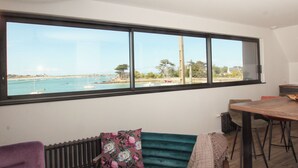Ein Zimmer mit großem Fenster und Meerblick, einem Esstisch und einer Heizung.