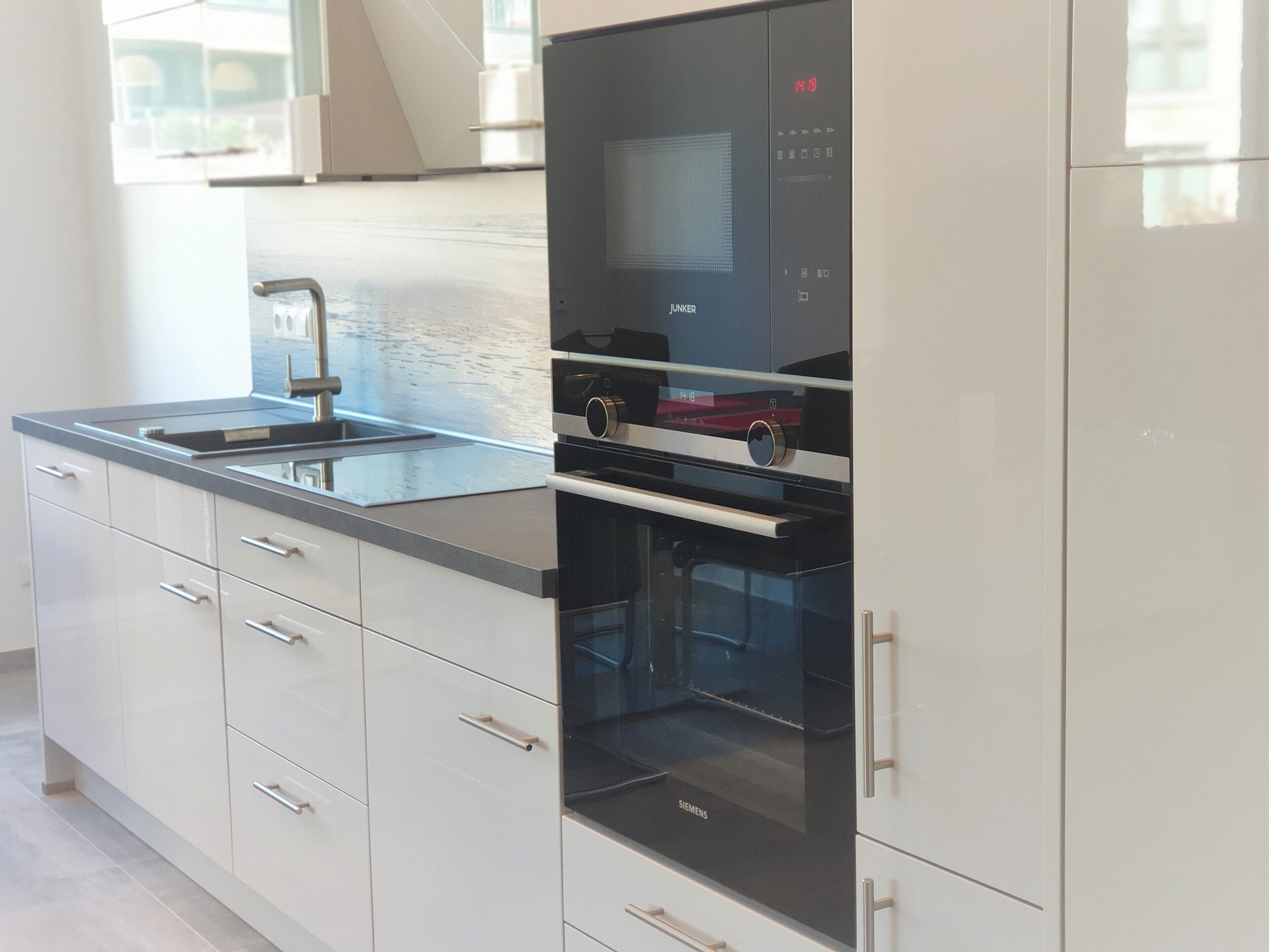 A modern kitchen with a built-in oven, a microwave, and a sink.