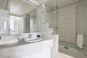 A modern bathroom with a glass shower enclosure, a marble sink, and a large mirror.