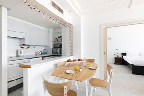 Une cuisine moderne avec des meubles blancs, une table à manger en bois et un coin repas pour le petit-déjeuner.