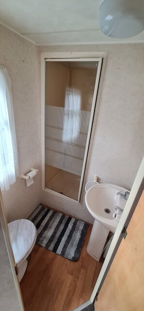 A compact bathroom with a toilet, a sink, and a shower enclosure. - Staycation Opposite Fantasy Island Ingoldmells (Skegness)