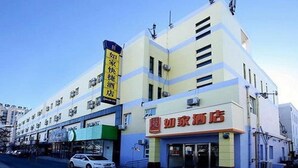 Ein Hotel mit auffälliger Beschilderung in chinesischen Schriftzeichen, einer modernen Fassade und einem gut sichtbaren Eingang.