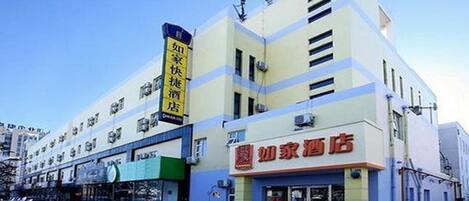 A hotel with a prominent sign in Chinese characters, a modern facade, and a visible entrance.
