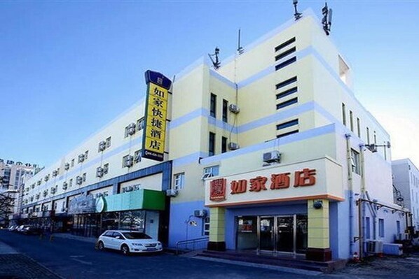 A hotel with a prominent sign in Chinese characters, a modern facade, and a visible entrance.
