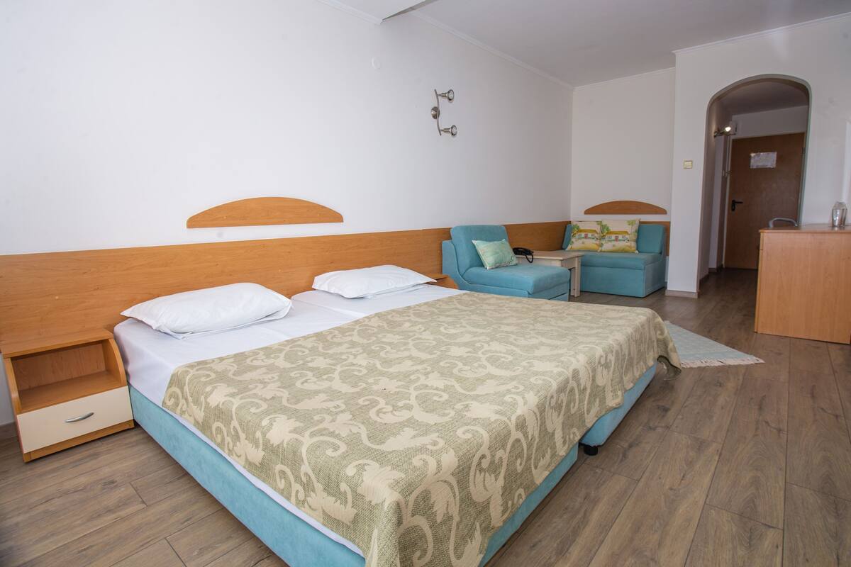 A bedroom with a bed, a nightstand, a desk, and a chair.