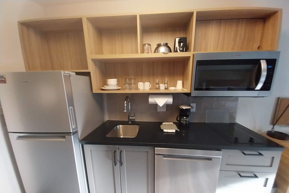 A compact kitchen with a refrigerator, microwave, sink, and cabinets.