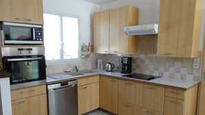 A modern kitchen with wooden cabinets, a built-in oven, a dishwasher, and a coffee maker.
