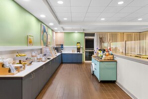 A modern kitchen with a long counter, cabinets, and a small island with a sink. - Spark by Hilton Dothan (Dothan)