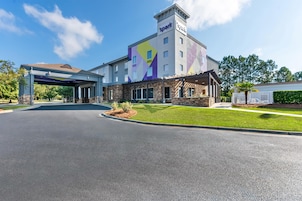 Un hotel con ingresso coperto, facciata in pietra e un murale colorato.