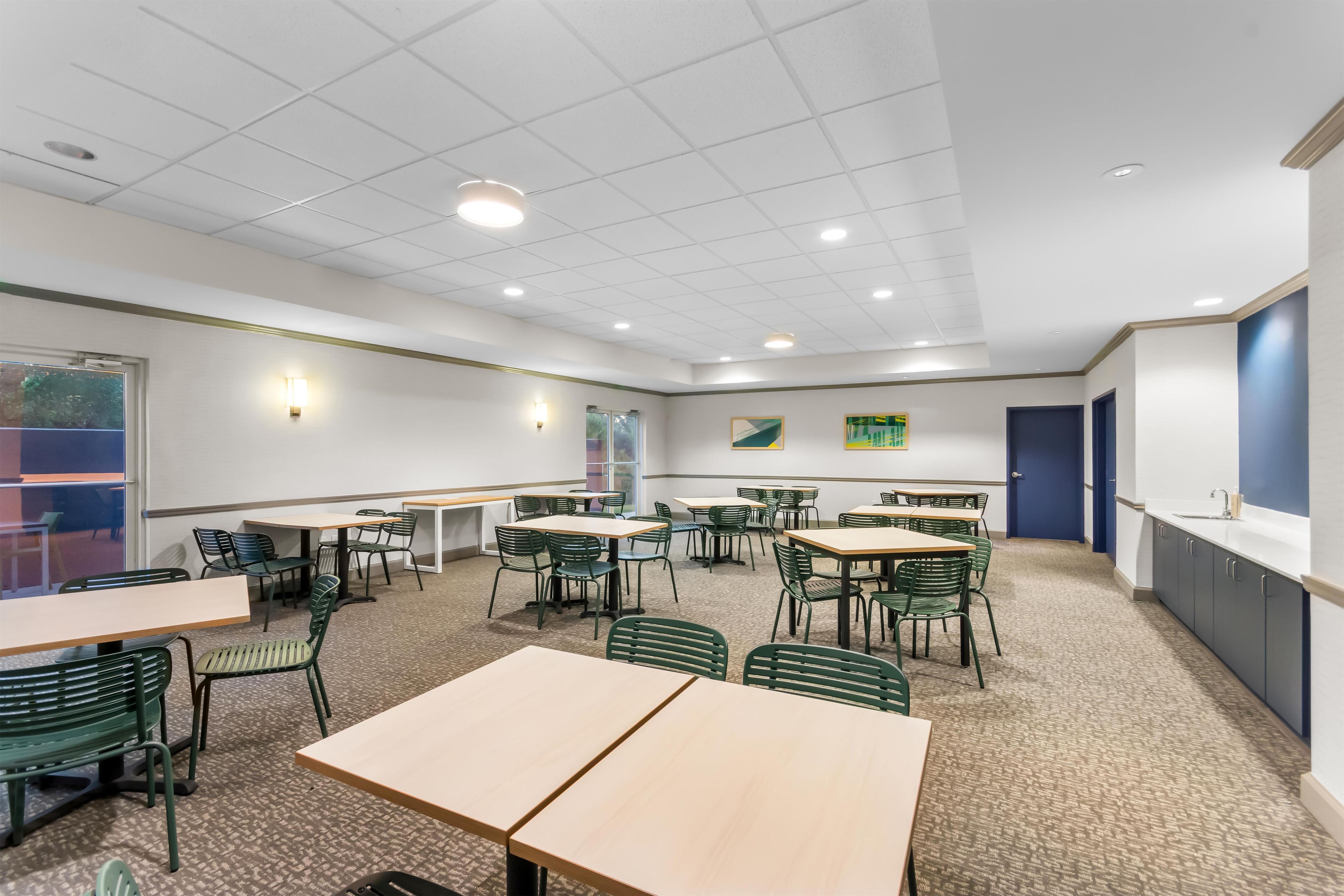 A conference room with tables and chairs, a whiteboard, and a door.