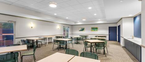 A conference room with tables and chairs, a whiteboard, and a door.