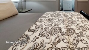 Camera d'albergo con un letto, un comodino, una lampada e un bagno visibile attraverso una porta aperta.