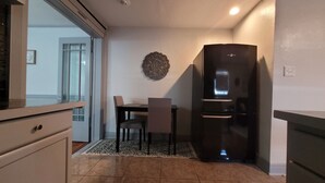 Una cucina compatta con un frigorifero, un tavolo da pranzo con sedie e un tappeto decorato.