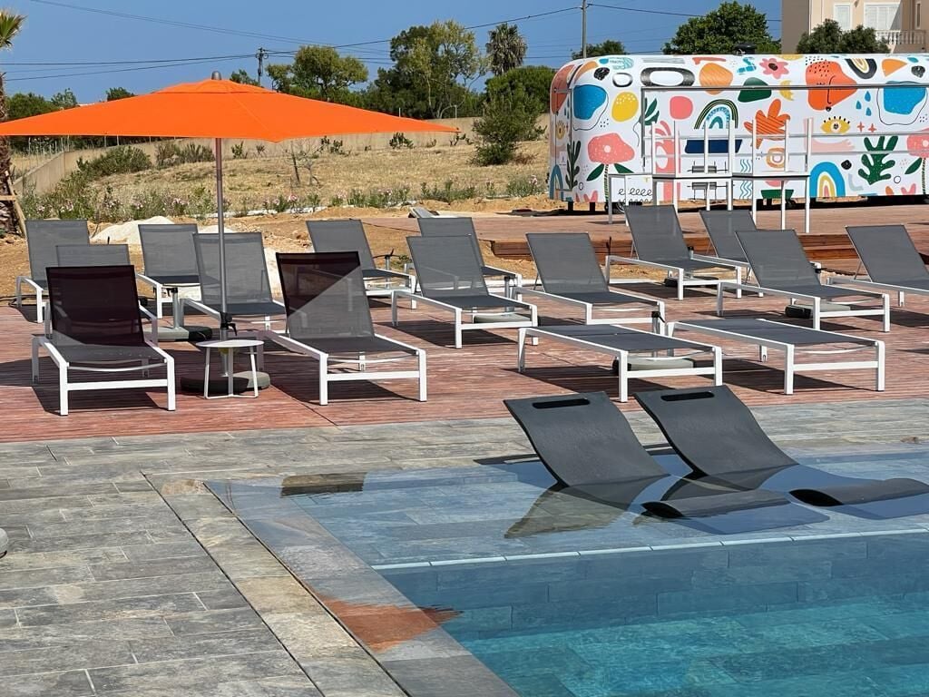 A poolside area with lounge chairs and a colorful food truck in the background.