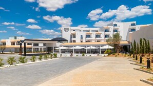 Un hotel moderno con un patio central, mobiliario exterior y un cielo azul despejado.