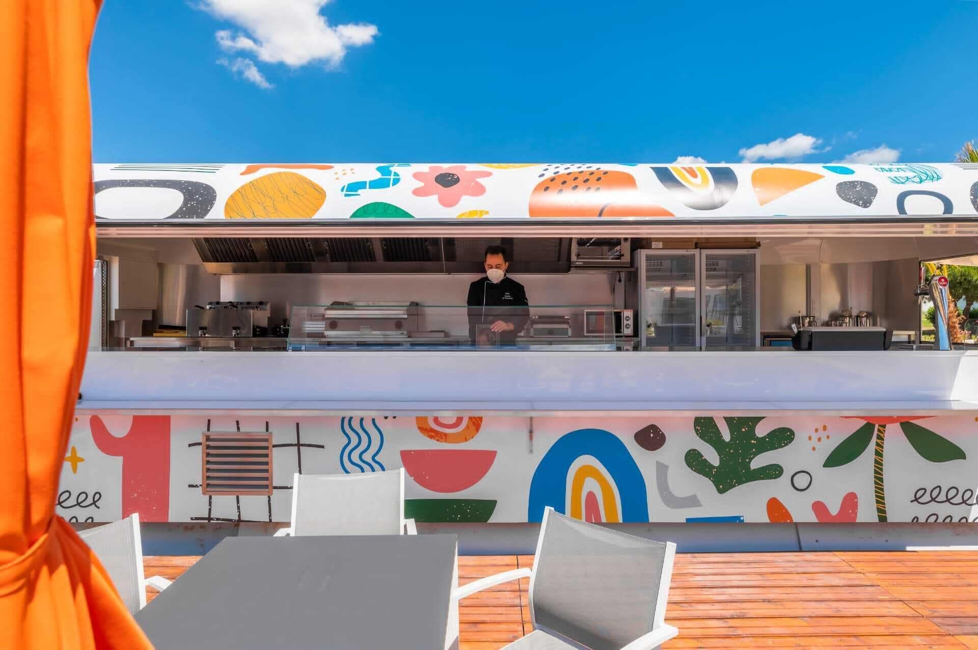Un restaurant à la façade colorée, avec un chef qui travaille derrière le comptoir.