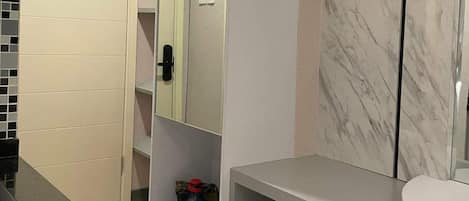 Une salle de bain moderne avec un meuble-lavabo en marbre, un petit réfrigérateur et un grand miroir.