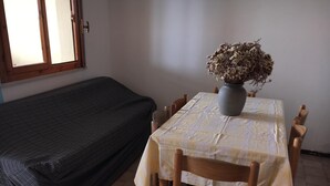 A room with a bed, a table with a vase of dried flowers, and a window. - [lido Adriano] Appartamento con Vista Mare (lido adriano)