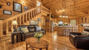 A spacious log cabin interior with a living area, dining space, and kitchen.