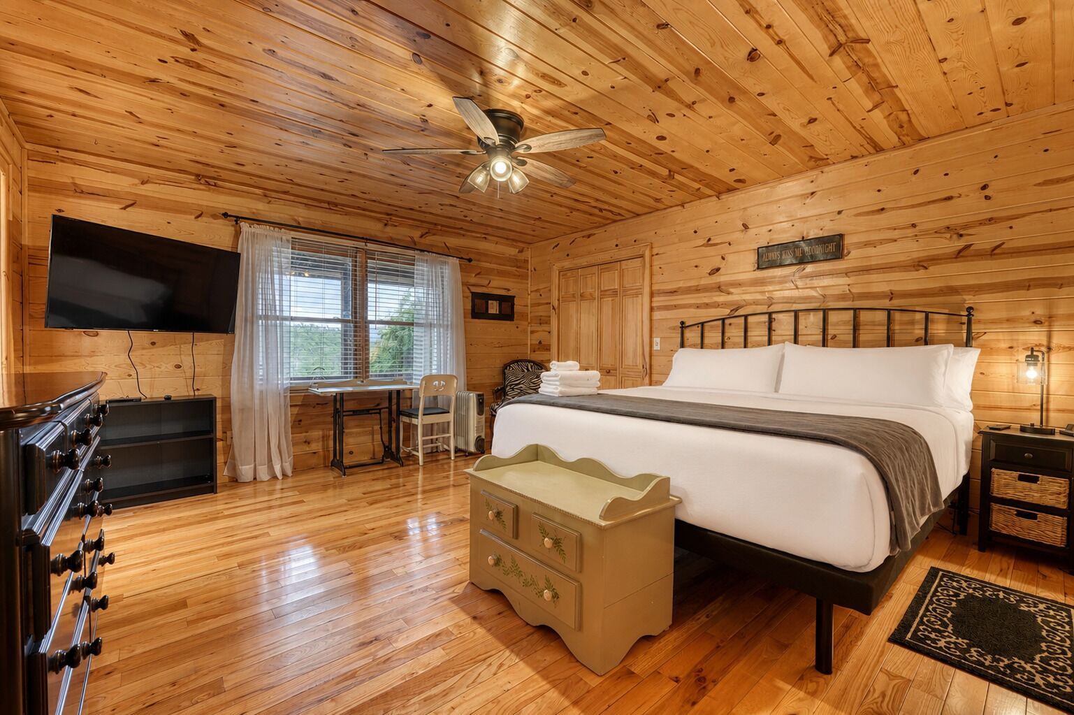 Una habitación tipo cabaña de madera con una cama, un escritorio, un televisor y una chimenea.
